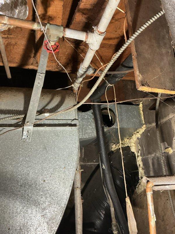 Assessed and serviced a leaking shut-off valve inside the water meter. Inspected the galvanized main water line and electric water heater for potential replacement. Documented existing conditions including pipe connections in the crawlspace area and current water heater installation with associated plumbing fixtures.