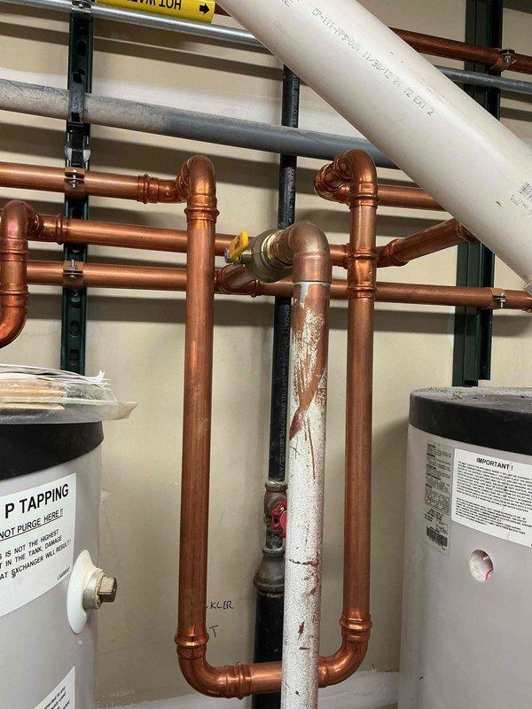 Installed new check valve as requested and replaced damaged elbow fitting. Modified plumbing configuration with unions to allow future isolation of lines and simplified check valve replacement if needed. Work completed on HTP water heater system with associated copper and PVC piping network.