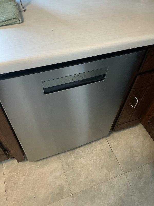 Responded to water leak complaint in kitchen area where water was seeping up through floor. Diagnosed issue as internal leakage from dishwasher discharge pipe. Shut off water supply to dishwasher and advised customer to contact appliance technician as unit is still under manufacturer warranty.