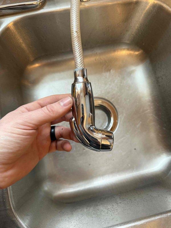 Diagnosed and repaired sticking side sprayer on Moen kitchen faucet by disassembling the unit, freeing the action button, and applying lubricant to prevent future sticking. Provided customer with replacement options should the issue persist.