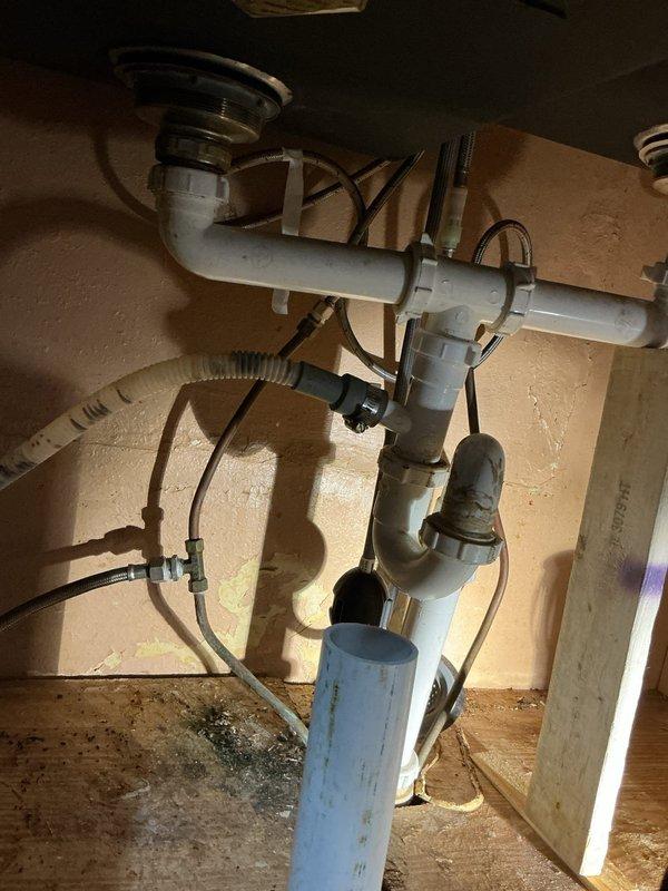 Diagnosed and repaired kitchen sink drainage system that was improperly installed by previous homeowner. Found disconnected piping and incorrectly installed dishwasher water line. Removed all makeshift plumbing components and replaced with proper PVC drainage assembly, including new P-trap and appropriate fittings to ensure proper water flow and prevent leaks.