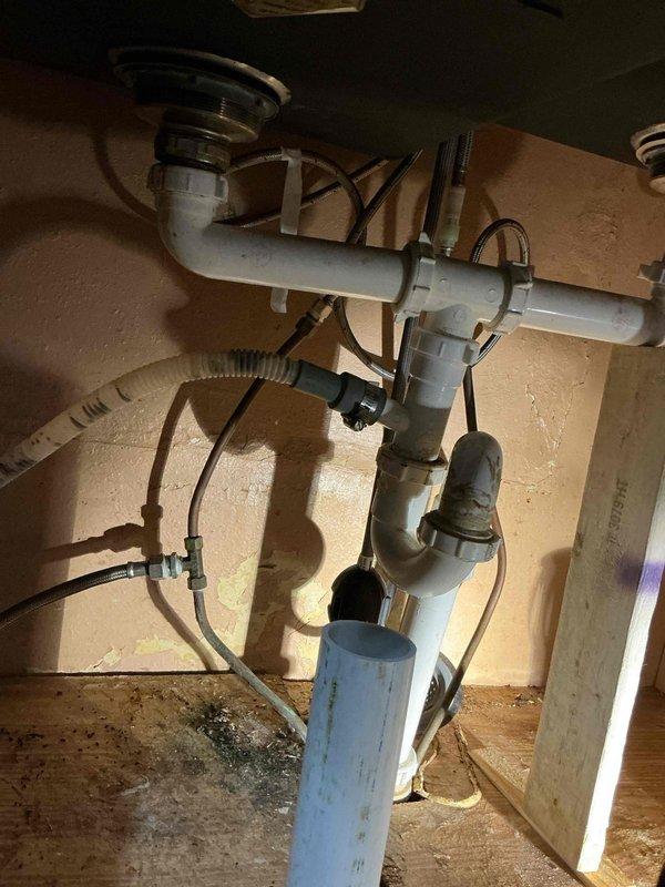 Diagnosed and repaired kitchen sink drainage system that was improperly installed by previous homeowner. Found disconnected piping and incorrectly installed dishwasher water line. Removed all makeshift plumbing components and replaced with proper PVC drainage assembly, including new P-trap and appropriate fittings to ensure proper water flow and prevent leaks.