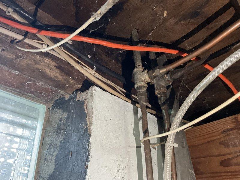 Conducted comprehensive plumbing inspection of basement/crawl space infrastructure. Documented condition of exposed plumbing system including copper supply lines, PEX piping, valves, and connection points. Noted aging wooden structural elements with no significant deterioration, though evidence of minimal moisture exposure was observed on concrete/plaster wall surfaces.