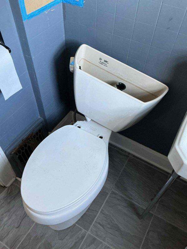 Removed broken toilet with damaged porcelain. Successfully installed new white toilet in corner bathroom with blue-tiled walls, ensuring proper connection to existing plumbing. Installation completed with proper sealing and functionality testing.