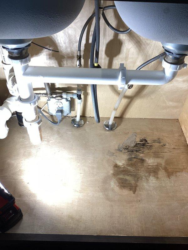 Repaired kitchen sink leak by installing a new continuous waste assembly after identifying that the existing waste pipe was separating. Inspection revealed water damage to the cabinet base, indicating ongoing leakage. System now functioning properly with no leaks observed at connection points.