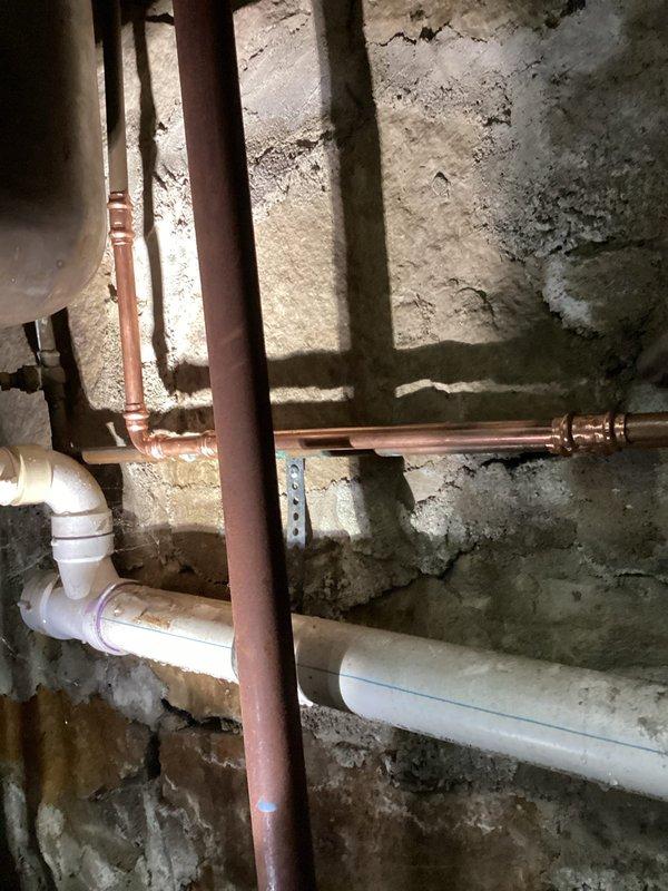 Responded to a service call for a leaking ball valve below a utility sink in the basement. Upon inspection, identified a compromised ball valve in the copper supply line mounted against the concrete wall. Removed the defective valve and installed a new one, successfully resolving the leak issue.