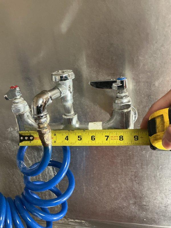 Inspected commercial dual-handle faucet assembly with broken spout and no existing shut-off valve. Measured 8" center-to-center spread and documented current installation with photographs. Determined existing valves were not sealing properly when closed; submitted parts order form for two replacement faucets and necessary shut-off valve components.