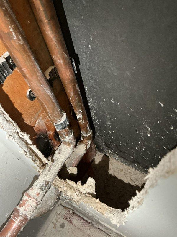 Responded to leak repair service call where customer had opened wall to expose a broken 3/4" copper pipe damaged by freezing. Replaced the damaged copper section, but upon restoration of water service, multiple additional leaks were detected within the wall cavity. Documentation with photos shows aged copper piping with patina throughout the exposed area and significant wall damage requiring further repair. Additional service appointment needed to address all remaining leaks.