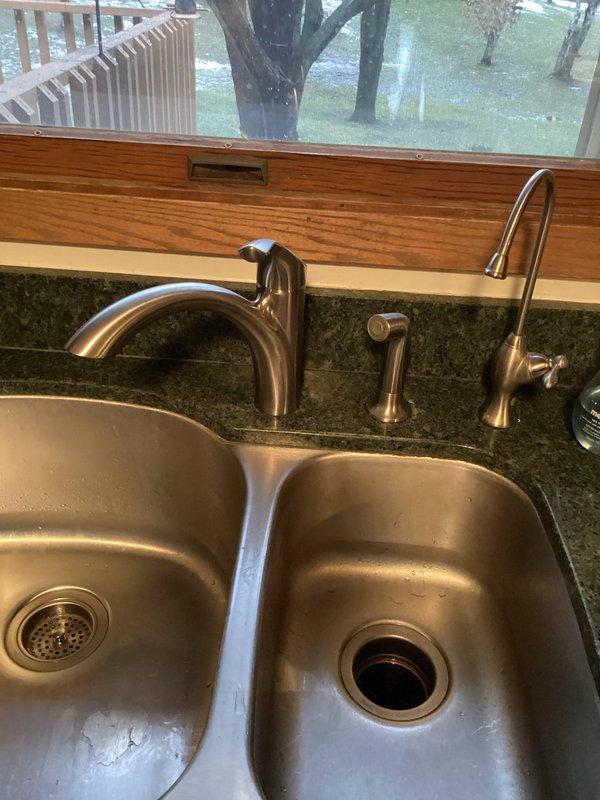 Successfully installed customer-supplied kitchen faucet in existing stainless steel double-basin sink. Properly connected all supply lines and verified operation of main faucet and side fixtures. No leaks observed at connections after installation and testing.