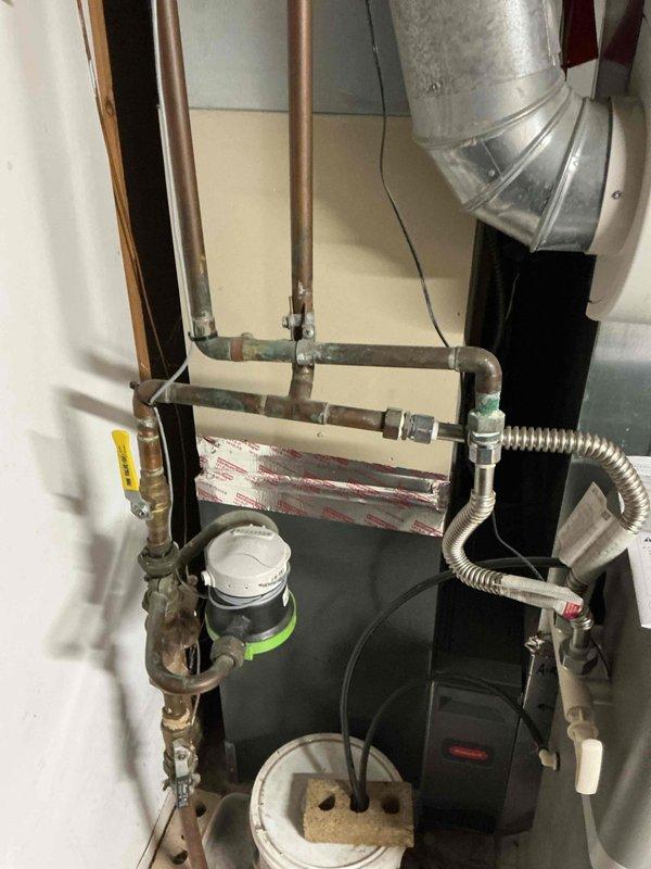 Inspected water heater in utility area that was leaking from internal components. Observed corrosion at connection points and conducted diagnostic assessment of the system, which includes copper piping, pressure regulator, and associated plumbing fixtures. Recommended complete water heater replacement due to internal failure that cannot be repaired.