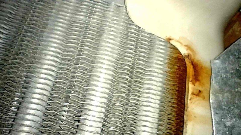 Inspected furnace for reported leak and determined water damage originated from AC unit that had been leaking during summer months. Observed significant rust and water stains where condensation overflowed from evaporator drain pan and pooled on shelf supporting evaporator coil, with moisture penetrating furnace housing and corners of evaporator case. Scheduled follow-up AC tune-up to diagnose root cause (possible clogged drain line or refrigerant charge issues causing ice formation).