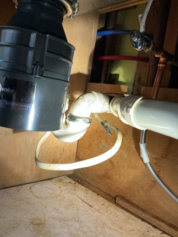Responded to service call for kitchen sink leak affecting downstairs area. Upon inspection, discovered rotted garbage disposal unit was source of water leakage. Successfully removed damaged unit and installed new Badger Series garbage disposal, properly connecting all PVC drainage piping and ensuring proper seals at drain flange. Final testing confirmed complete resolution of leak issue with no further water intrusion.