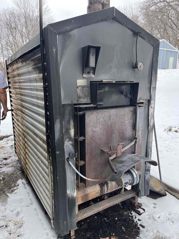 Responded to service call for an outdoor wood burner heating system with no heat supply to the residence. Diagnosed low water level causing airlock in the circulation system despite functioning pump. Restored proper operation by adding water to correct level, purging air from lines, and verifying circulation resumed with heat transfer to indoor coil. System returned to normal operation with water temperature at 180° and proper pressure maintained.