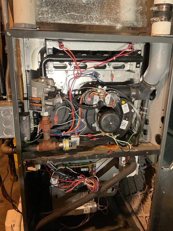 Performed annual maintenance on 5-year-old Amana single stage LP furnace. Found and removed plastic wrappers from blower wheel and adjusted speed taps up one level to correct excessive temperature rise. Noted plugged filter and recommended client ensure all vents remain open and check filter more frequently. Observed rust on deck beneath inducer caused by previous leaky flue pipe connection, though no active condensate present today.