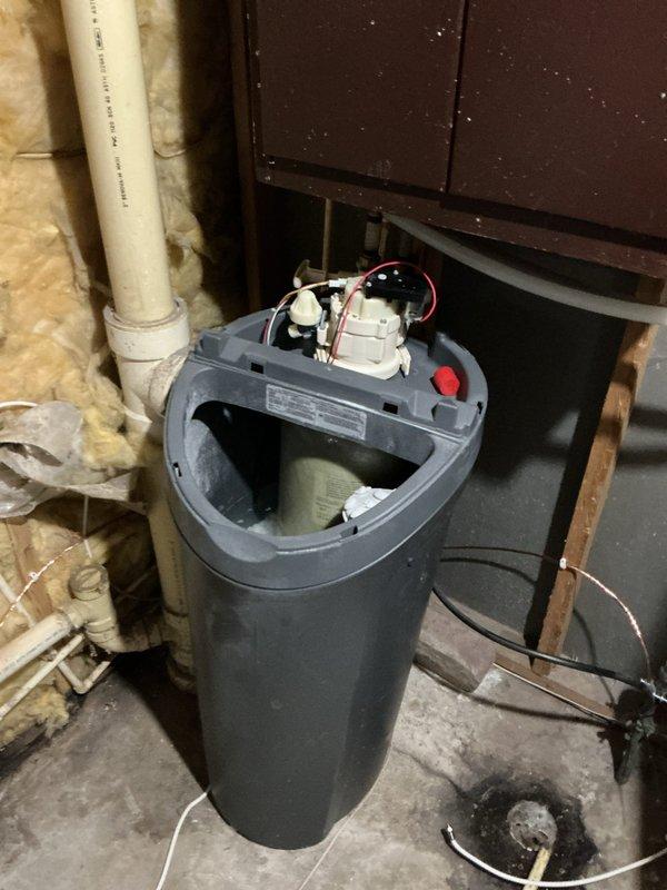 Diagnosed malfunctioning water softener and determined control board failure was the cause; service advisor scheduled to provide replacement quotation. Repaired leaking toilet by addressing threaded connection issue below the fixture. Successfully fixed leak on stack and documented condition of water treatment system with photos showing internal components and surrounding utility area.