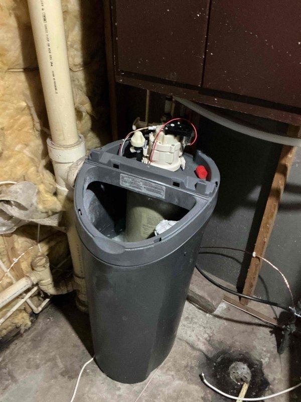 Diagnosed malfunctioning water softener and determined control board failure was the cause; service advisor scheduled to provide replacement quotation. Repaired leaking toilet by addressing threaded connection issue below the fixture. Successfully fixed leak on stack and documented condition of water treatment system with photos showing internal components and surrounding utility area.