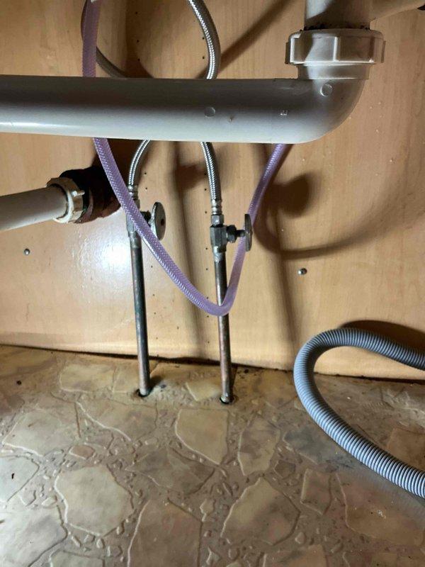 Repaired water leak in kitchen plumbing by replacing customer-supplied kitchen faucet and fixing compromised dishwasher supply line connection. Visual inspection confirmed successful repair with no residual leaks in the under-sink assembly, including proper function of all supply lines and drainage components.
