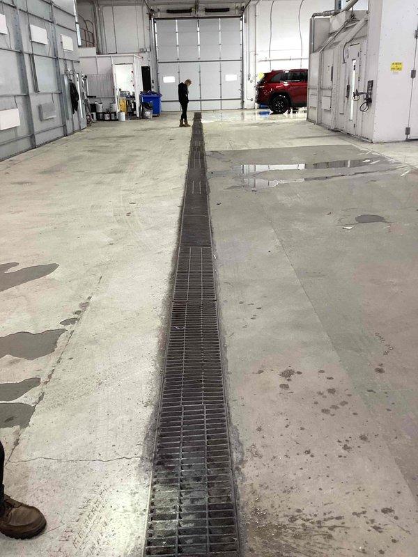 Responded to service call for clogged wash bay drainage system. Inspection revealed significant debris accumulation in the floor drainage grates, causing water backup across the concrete floor. Manually cleaned out all obstructed drainage channels, removing built-up sediment and debris to restore proper water flow and drainage functionality.