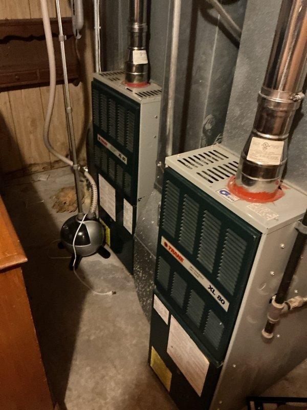Performed scheduled maintenance tune-up on two furnace systems (93 and 94 year models). Identified critical issues in upstairs unit including cracked heat exchanger, gas valve malfunction, and oil leakage from blower motor. Basement unit inspection revealed blower motor oil leakage and thermostat placement concerns. Documented system conditions with detailed component photography for replacement recommendations.