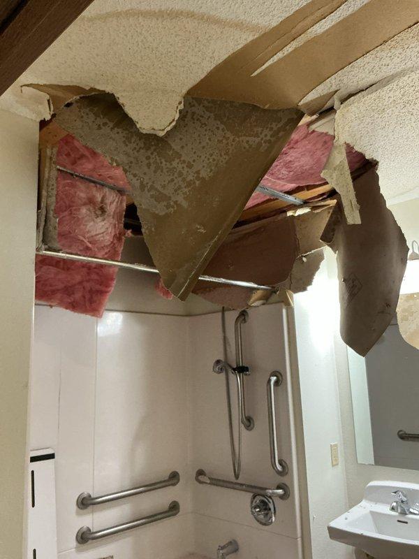 Responded to emergency call for water damage in vacant unit bathroom. Discovered cracked tub drain with no putty underneath causing water leakage from upstairs bathroom, resulting in significant ceiling collapse and exposed insulation. Replaced damaged section of tub drain and verified repair with leak test.