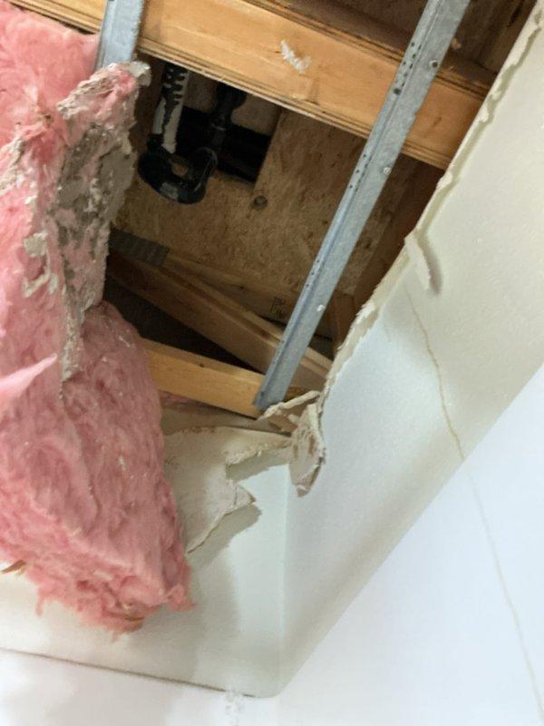 Responded to emergency call for water damage in vacant unit bathroom. Discovered cracked tub drain with no putty underneath causing water leakage from upstairs bathroom, resulting in significant ceiling collapse and exposed insulation. Replaced damaged section of tub drain and verified repair with leak test.