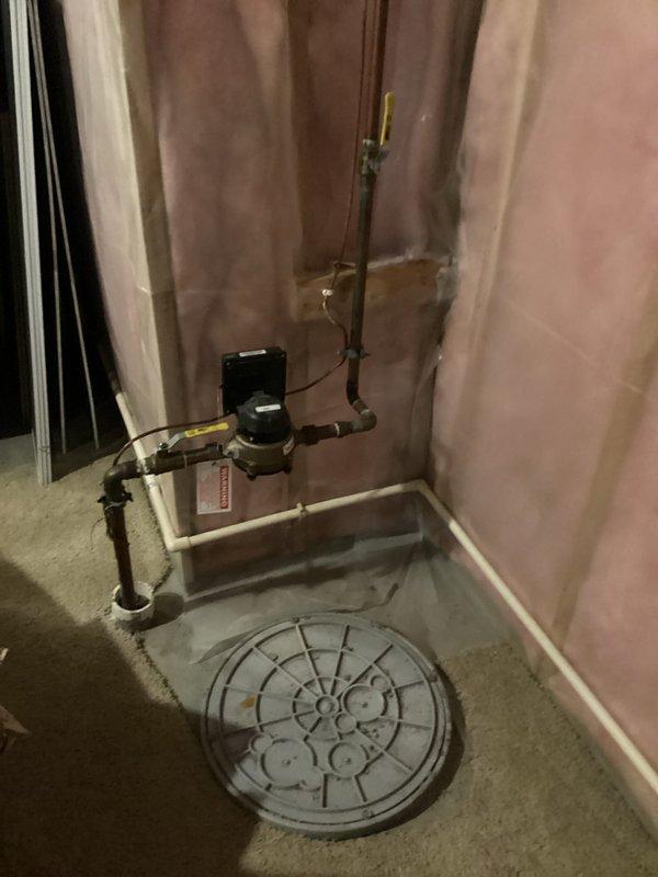 Conducted comprehensive plumbing inspection of residential property, examining bathroom shower/tub installation with chrome fixtures and diverter spout in good working condition. Basement inspection revealed properly installed sump pump system with PVC and metal piping connections, functioning valve, and appropriate drainage setup with no visible leaks or operational issues detected.