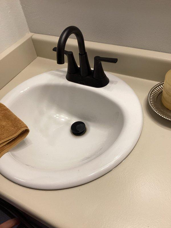 Completed plumbing inspection for family connection. Inspected newly remodeled bathroom and kitchen fixtures, noting proper installation of bathroom sink with matte black faucet and kitchen double basin with chrome fixtures. Identified and documented missing valve on exterior lawn faucet requiring attention.