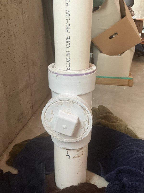 Diagnosed and inspected a reported leak from the square plug area of a T-shaped fitting on a PVC-DWV pipe in the basement. Visual examination confirmed a cracked tee junction, which was also contributing to a sewer backup issue. Referred customer to drain specialists for the backup problem.