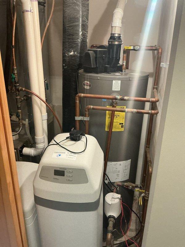 Responded to water leak report near customer's furnace. Inspected utility room containing Richmond water heater and dual water softener system with all connecting copper and PVC piping. Found no active leaks in the water treatment equipment or water heater installation during thorough examination of the mechanical room.
