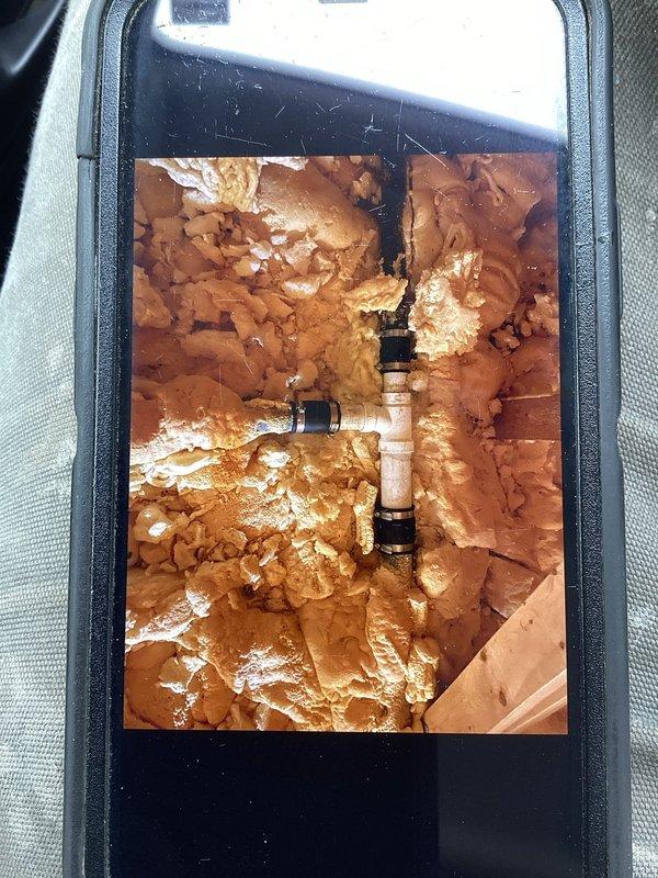 Responded to a water leak call at a residential property where an ABS 90 fitting was improperly glued and leaking from the vent boot in the attic. Accessed the confined space, removed affected spray foam insulation to expose the damaged plumbing, and replaced two 90-degree fittings with 2" PVC components properly tied into the existing ABS system. Leak was successfully repaired and system tested to confirm resolution.