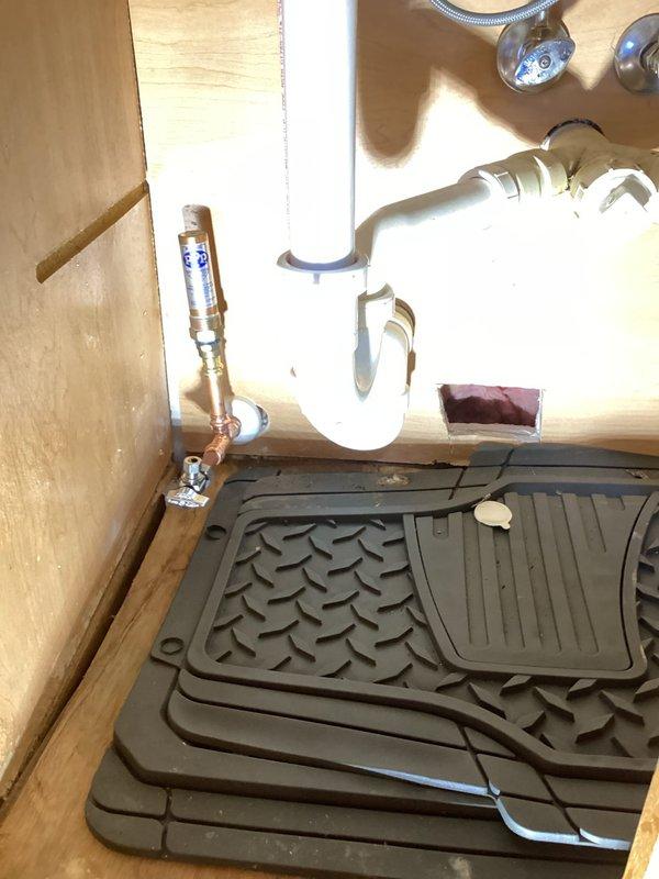 Responded to a water leak service call where the existing P-trap and dishwasher plumbing under the kitchen sink had failed. Successfully replaced the leaking P-trap assembly and completely repiped both the dishwasher water supply line and waste pipe, which required reconfiguration of obstructing water lines. Photographic documentation was taken of the cabinet access area and completed under-sink plumbing installation featuring the new PVC drainage system and copper supply lines with brass shut-off valve.