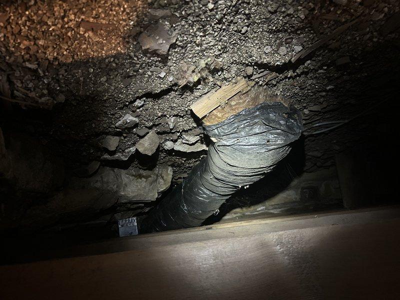 Inspected disconnected 8-inch insulated flex duct in underfloor area that had been damaged by rodents. Assessed approximately 12 feet of ductwork requiring replacement, with visible holes and separation at connection points. Documented condition with photographs showing the deteriorated metal ductwork in the crawlspace environment.