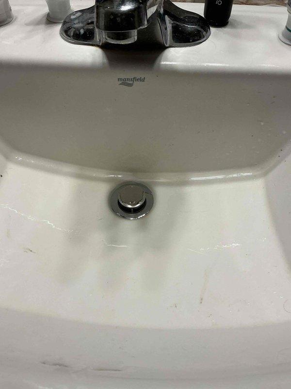 Responded to service call for a basement sink with foreign object obstruction. Discovered the trip lever was rusted off on the drain, allowing items to fall into the plumbing. Replaced the entire pop-up assembly on the Mansfield porcelain sink and verified proper operation with leak testing.