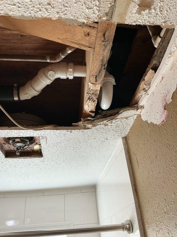 # Plumbing Service Report - Shower/Tub Drain Repair

## Work Performed

Responded to service call for upstairs bathroom with multiple drainage issues affecting both the lavatory sink and bathtub/shower unit. Upon inspection, identified failed gaskets on sink drain assembly and complete drainage failure in bathtub due to obsolete drum trap configuration.

The primary challenge involved the bathtub drain system, which was equipped with an outdated drum trap that prevented effective snaking and clearing of the blockage. Drum traps, while common in older plumbing installations, are prone to collecting debris and creating persistent drainage problems due to their design. Standard drain cleaning equipment cannot navigate these fixtures effectively.

To resolve the issue permanently, removed the existing drum trap assembly and replaced it with a modern P-trap configuration. This required accessing the plumbing through the ceiling below the bathroom, creating an opening to reach the drain line