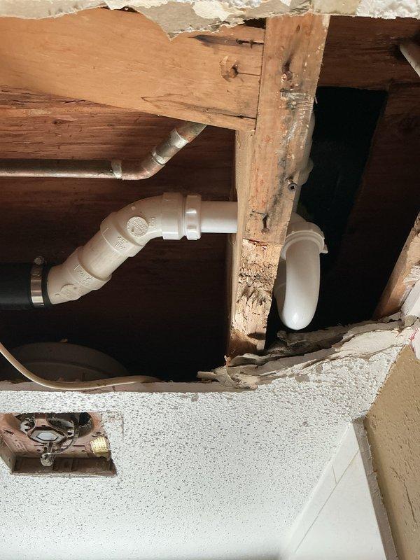 # Plumbing Service Report - Shower/Tub Drain Repair

## Work Performed

Responded to service call for upstairs bathroom with multiple drainage issues affecting both the lavatory sink and bathtub/shower unit. Upon inspection, identified failed gaskets on sink drain assembly and complete drainage failure in bathtub due to obsolete drum trap configuration.

The primary challenge involved the bathtub drain system, which was equipped with an outdated drum trap that prevented effective snaking and clearing of the blockage. Drum traps, while common in older plumbing installations, are prone to collecting debris and creating persistent drainage problems due to their design. Standard drain cleaning equipment cannot navigate these fixtures effectively.

To resolve the issue permanently, removed the existing drum trap assembly and replaced it with a modern P-trap configuration. This required accessing the plumbing through the ceiling below the bathroom, creating an opening to reach the drain line