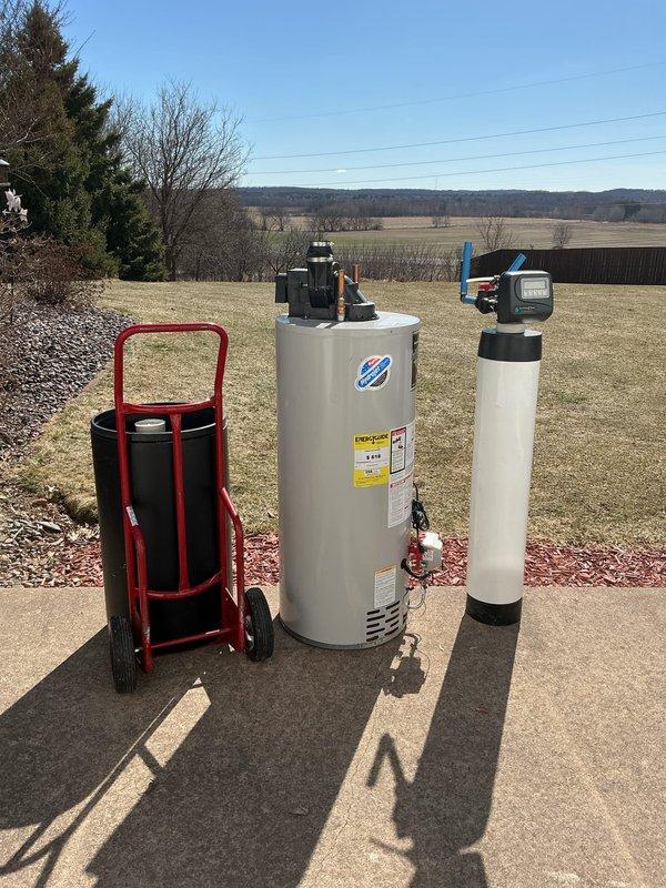 # Service Report: Water Heater Replacement

Responded to service call for leaking propane water heater. Upon arrival, confirmed active leak originating from bottom of existing unit, indicating tank failure. Diagnostic fee waived as replacement was clearly required.

Removed failed water heater and installed new 50-gallon power vent LP (propane) unit. Connected gas supply line with shutoff valve, installed proper venting system with PVC exhaust piping, and completed all water supply connections using copper piping. Verified proper electrical connections for power vent motor operation. Tested all connections for leaks and confirmed unit fired properly with adequate combustion and venting.

Per customer request, also removed old water softener system from premises. All removed equipment hauled away from property. Installation completed within scheduled service window. System operational and customer satisfied with completed work.