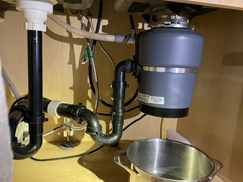Responded to service call for leaking garbage disposal that had reportedly fallen off, preventing dishwasher use. Upon inspection, determined that the locking ring on the 3/4HP InSinkErator disposal unit had come loose, causing the leak and instability. Tightened the locking ring to the locked position using the manufacturer's included tool, securing the disposal properly to the sink mounting assembly. Verified unit was stable and leak-free after repair. No replacement was necessary.