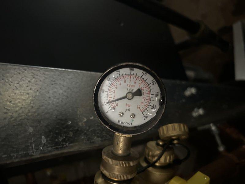 Responded to no heat call on boiler system displaying low water tank error code. Upon inspection, discovered the boiler was critically low on water and the auto-fill system was not functioning. Diagnosed the issue to a failed backflow preventer blocking water flow to the boiler. Disconnected the backflow preventer from the auto-fill assembly and opened the upstream valve, confirming no water flow through the device. Attempted to free the stuck internal components of the backflow preventer without success. Manually filled the boiler system to restore temporary operation and bring system pressure to safe operating levels. Backflow preventer requires replacement to restore automatic water feed functionality and prevent future low water conditions.