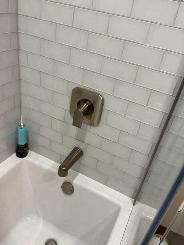 Completed comprehensive plumbing inspection of residential property including bathroom fixtures and water treatment system. Inspected bathtub, shower controls, tub spout, and tiled surround—all fixtures operating properly with no leaks or deficiencies noted. Examined whole-house water filtration system with VIQUA filter housing, copper piping connections, compression fittings, and isolation valve; system functioning correctly with no service requirements. No corrective action needed.