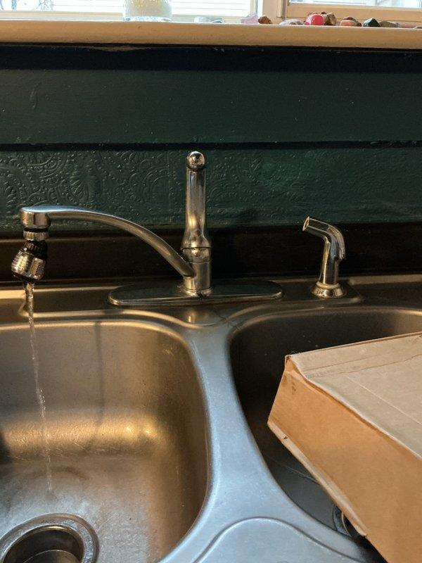 Responded to kitchen sink leak occurring only during dishwashing. Upon inspection, identified deteriorated spray hose on existing kitchen faucet assembly causing water to spray underneath sink cabinet during use. Removed old single-handle chrome faucet with deteriorating spray attachment from stainless steel double-basin sink. Installed new single-handle kitchen faucet with separate side spray assembly. Tested all connections under load to verify proper operation and confirmed no leaks present during normal use and spray function activation.