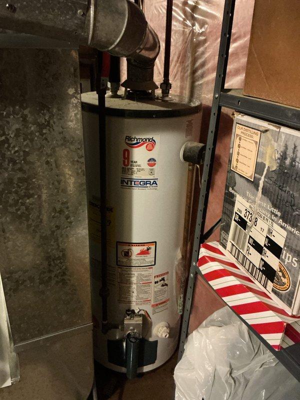 Responded to a water leak in the mechanical room, initially suspected to originate from either the water heater or water softener. Upon inspection, identified the source as a failed water heater tank with rust-through deterioration at the bottom, causing active water discharge onto the floor. Removed the compromised unit and installed a replacement Richmond Integra 40-gallon natural gas water heater with standard atmospheric venting to match the existing configuration. Completed all necessary connections including gas line, cold water supply, hot water distribution, temperature and pressure relief valve discharge piping, and exhaust venting. Verified proper operation, checked for leaks at all connection points, and confirmed adequate combustion and draft performance.