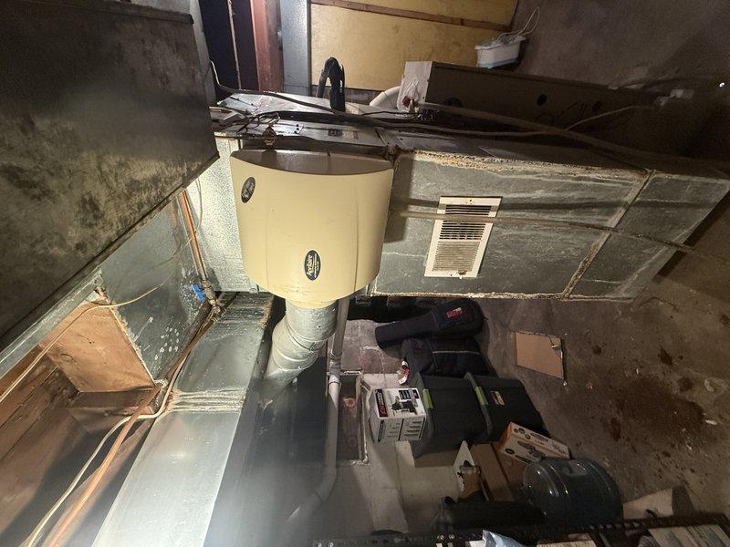 Responded to service call regarding significant hole in return ductwork running between floor joists. Upon inspection, discovered extensive corrosion and deterioration of duct material caused by moisture damage. Investigation revealed multiple contributing factors: current humidifier showing signs of leakage, evidence suggesting previous steam humidifier installation by prior homeowners, and staining with odor present at upstairs vent directly above damaged area, likely from pet urine penetration through flooring. Determined that cumulative moisture exposure from humidifier leakage and organic contamination led to accelerated metal degradation and structural failure of return duct. Documented conditions with photographic evidence showing rust accumulation and compromised ductwork integrity. Replaced damaged section of return ductwork to restore proper system function and prevent air quality issues.