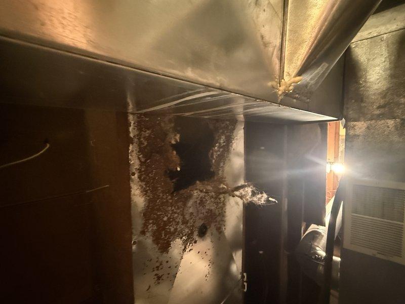 Responded to service call regarding significant hole in return ductwork running between floor joists. Upon inspection, discovered extensive corrosion and deterioration of duct material caused by moisture damage. Investigation revealed multiple contributing factors: current humidifier showing signs of leakage, evidence suggesting previous steam humidifier installation by prior homeowners, and staining with odor present at upstairs vent directly above damaged area, likely from pet urine penetration through flooring. Determined that cumulative moisture exposure from humidifier leakage and organic contamination led to accelerated metal degradation and structural failure of return duct. Documented conditions with photographic evidence showing rust accumulation and compromised ductwork integrity. Replaced damaged section of return ductwork to restore proper system function and prevent air quality issues.