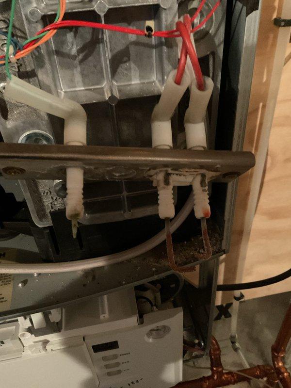 Responded to repeat service call for boiler displaying EA error code and flame failure condition. Upon inspection, found flame sensor severely deteriorated and nearly disintegrated, with spark electrodes also showing advanced wear. Discovered heat exchanger cleanout cover leaking exhaust gases into cabinet due to seized mounting bolt that cannot be properly tightened. Applied high-temperature silicone as temporary measure to maintain operation for domestic hot water needs. Removed and inspected flame sensing components, confirming replacement required. Submitted parts information to verify warranty coverage for heat exchanger, flame sensor, and ignitor assembly. Unit requires complete heat exchanger replacement for permanent repair; temporary measures implemented to maintain safe operation pending customer decision on repairs.