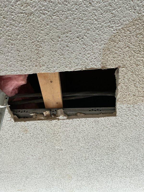 Responded to water leak emergency at 36-unit building where water was dripping through first-floor living room ceiling with multiple leak spots appearing. Building maintenance shut off water supply to prevent further damage. Cut exploratory access hole in ceiling to investigate source of leak. Upon inspection, confirmed no plumbing lines present in ceiling cavity above affected area. Determined leak originated from third-floor kitchen sink overflow that saturated through flooring and migrated down to first-floor ceiling. Advised maintenance to monitor ceiling for continued leakage and arrange drywall repair once area has fully dried and leak source has been confirmed resolved.