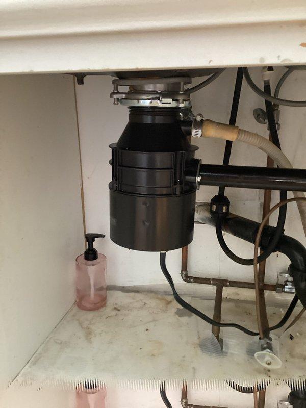 Replaced non-functional garbage disposal unit that had failed due to age. Removed existing disposal from under-sink mounting assembly, disconnected electrical wiring and drainage connections, and installed new disposal unit with proper plumbing connections and electrical hookup to restore full functionality to kitchen sink waste system.