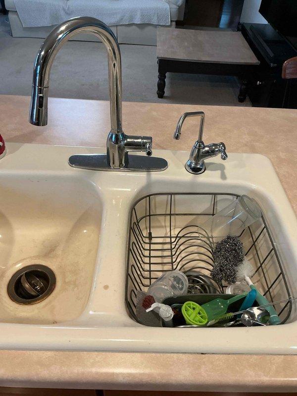 Disconnected water supply lines and drain plumbing for double-basin kitchen sink to facilitate countertop replacement. Shut off water valves beneath sink cabinet, removed P-trap and drain connections, and capped supply lines to prevent water damage during renovation. Return visit will be scheduled to reconnect all plumbing fixtures once new countertops are installed and kitchen island is repositioned.