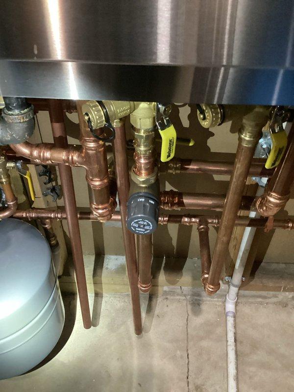 Responded to follow-up service call after boiler and indirect water heater installation to address domestic hot water temperature concerns. Performed comprehensive system diagnostics including boiler operation verification, DHW setpoint confirmation at 145°F, and external mixing valve inspection. Tested water temperature at sink faucets which measured correctly, but identified showers and tub running 10-15°F cooler than expected. Determined issue isolated to individual fixture mixing valves rather than boiler or primary DHW system. Coordinated plumber scheduling to adjust thermostatic mixing valves at affected fixtures to resolve temperature discrepancy.
