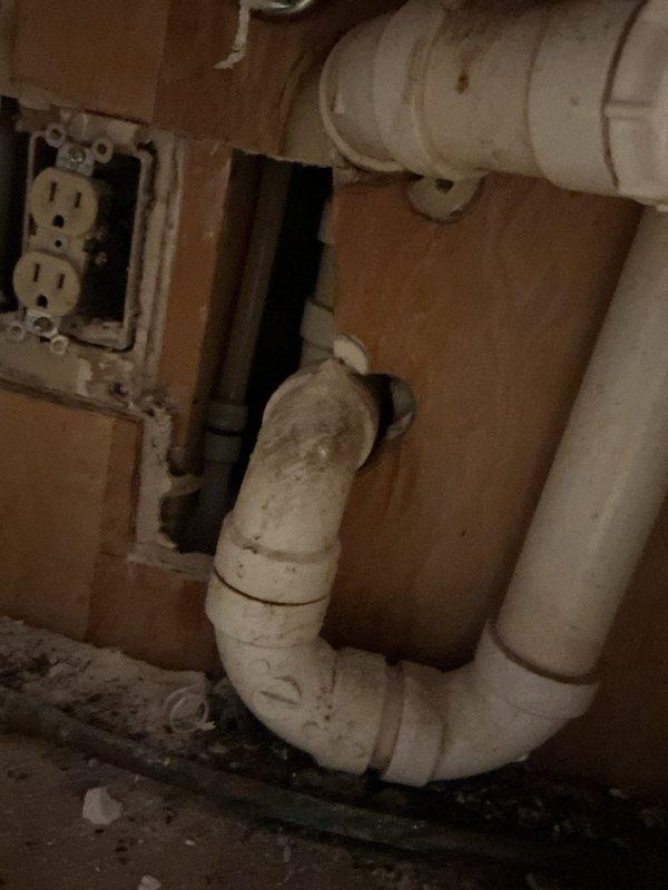 Responded to emergency water leak originating from upstairs bathroom causing active damage to main level ceiling. Upon arrival, main water supply had been shut off to prevent further damage. Investigation revealed cold water supply line serving kitchen had been compromised by rodent damage, resulting in hole in pipe and water discharge through ceiling. Created access points in kitchen cabinet and downstairs ceiling to expose damaged section of water line. Removed compromised pipe section and installed new piping using 90-degree elbow fitting and coupling to restore water supply line integrity. Restored main water supply and performed pressure test to verify repair and confirm no additional leaks present in affected area.