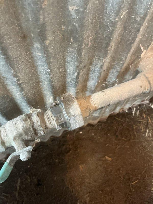 Responded to a water leak in a chicken coop where water was observed on the cement floor beneath exposed copper piping. Upon inspection, identified a loose union fitting on the water supply line that feeds the chicken watering bowl. Tightened the union connection to restore proper seal and eliminate the active leak. Assessed remaining floor moisture and determined it to be groundwater infiltration rather than plumbing-related. Photographed the repaired plumbing components and surrounding area for documentation purposes.